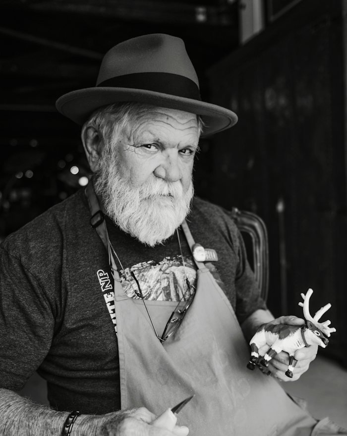 A senior craftsman holding carving tools